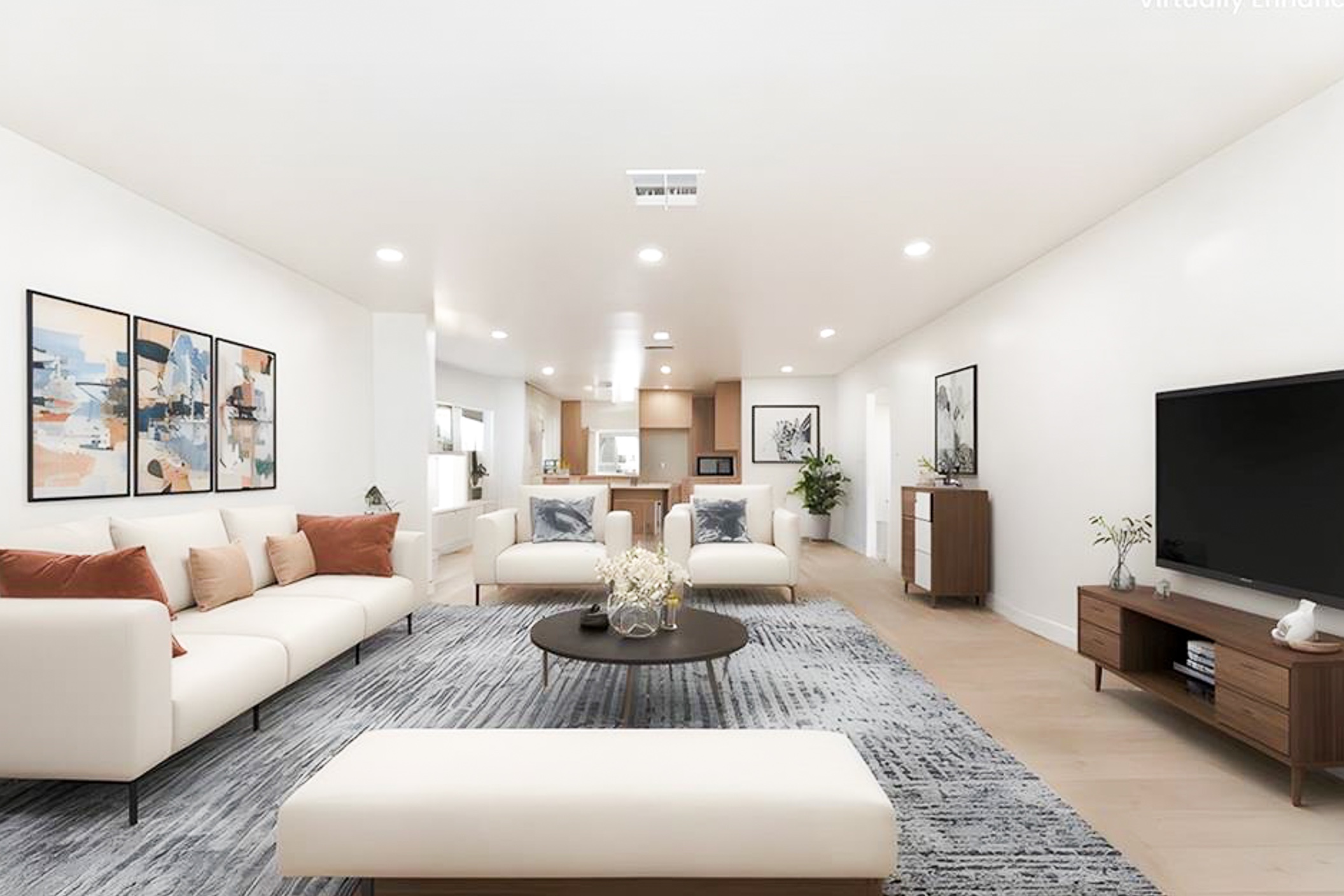 Open-plan living room in a completed remodel, with new light wood flooring and recessed lighting