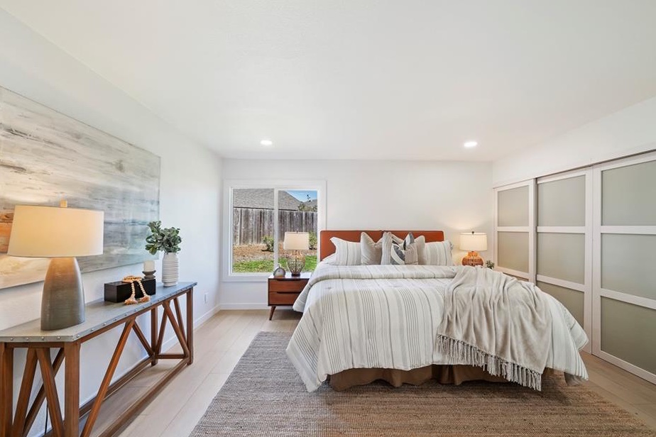 Primary bedroom with new wood flooring, fresh paint, and a large window, staged for sale